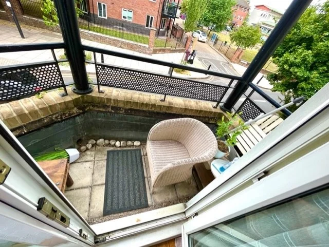 Private corner balcony overlooking a tree-lined street